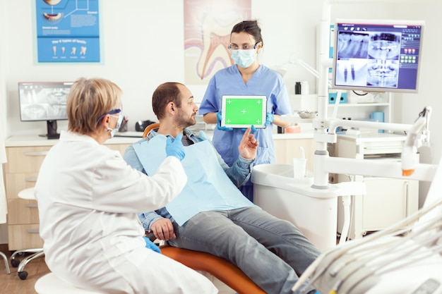 Enfermera médica sosteniendo simulacros de tableta chroma key de pantalla verde con pantalla aislada durante la consulta de somatología
