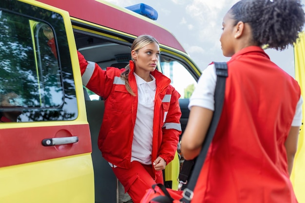 Foto gratuita enfermera paramédica y médico de urgencias en ambulancia con kit un paramédico parado en la parte trasera de una ambulancia junto a las puertas abiertas