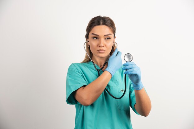 Enfermera de sexo femenino joven que mira el estetoscopio.