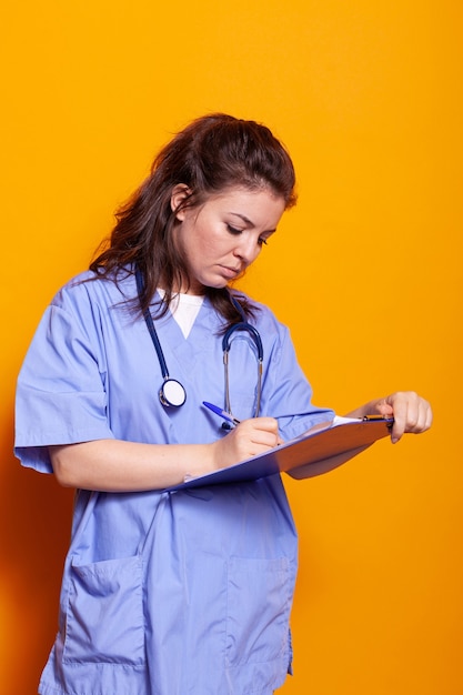 Enfermera con uniforme escrito en papeles del portapapeles