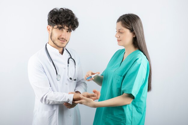 Enfermera en uniforme verde dando inyección al médico de sexo masculino.