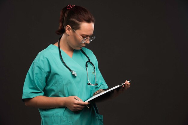 Enfermera en uniforme verde sosteniendo el espacio en blanco y mirando.
