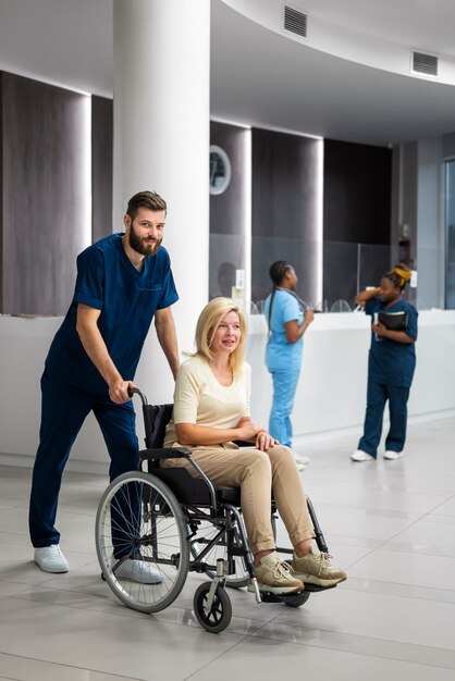 Enfermera de vista lateral que ayuda al paciente en silla de ruedas