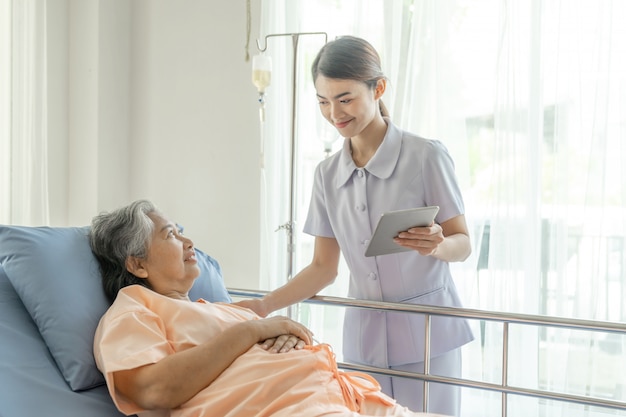 Las enfermeras están muy bien atendidas. Los pacientes de edad avanzada en cama de hospital sienten felicidad.