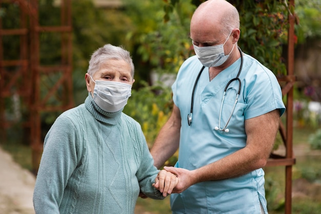 Enfermería masculina sosteniendo la mano de la mujer mayor para ayudarla a caminar