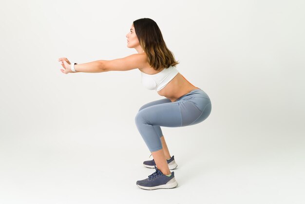 Enfocado en terminar mi rutina de ejercicios. Mujer deportiva en ropa activa haciendo ejercicios en cuclillas para fortalecer su cuerpo tonificado y delgado