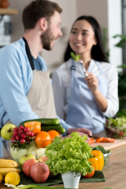 Enfoque borrosa pareja alimentación saludable ensalada detrás de pie de cocina