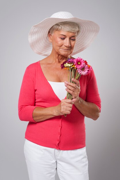Enfoque mujer mayor oliendo flores frescas
