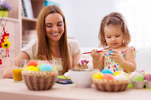 Enfoque niña pintando huevos de pascua con su madre