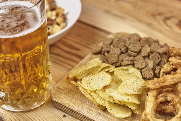 Enfoque suave de un vaso de cerveza artesanal espumosa con comida borrosa en una mesa de madera