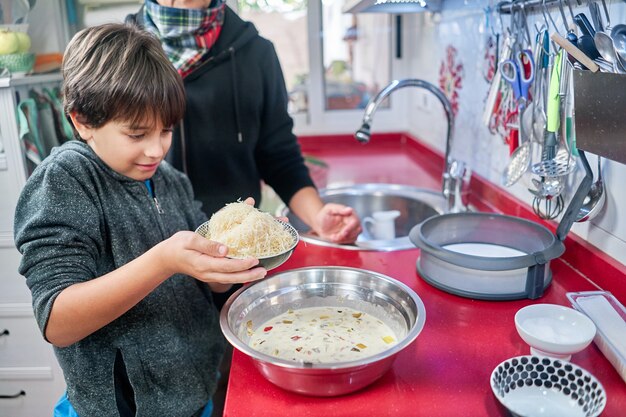 Enfoque superficial de una madre alegre cocinando con su pequeño hijo en una cocina