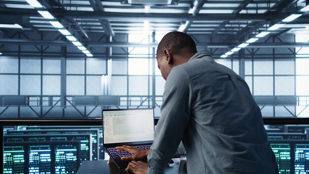 engineer in data center coding on laptop optimizing resource utilization