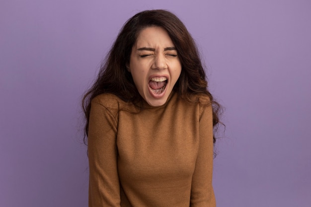 Foto gratuita enojado con los ojos cerrados hermosa joven vistiendo suéter de cuello alto marrón aislado en la pared púrpura