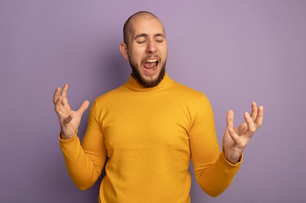 Foto gratuita enojado con los ojos cerrados joven guapo extendiendo las manos aisladas en la pared púrpura