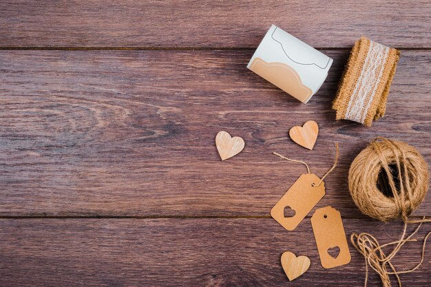 Enrollado encaje forma de corazón de madera; Etiquetas y carrete de yute en el escritorio de madera.