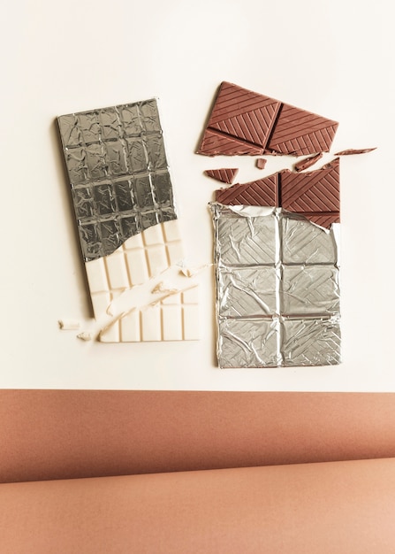 Enrollado papel de tarjeta con dos barras de chocolate contra el fondo blanco