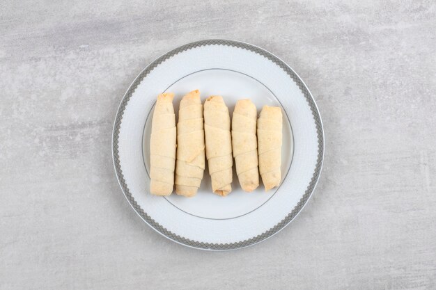 Enrolle las galletas en un plato, sobre la mesa de mármol.