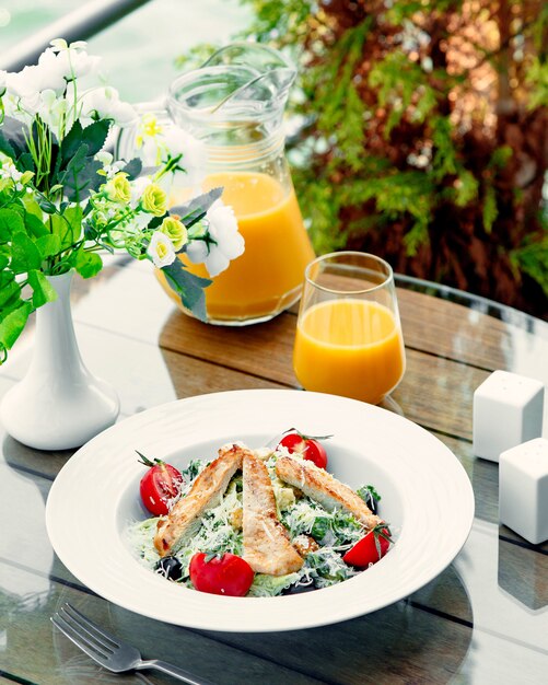 Ensalada Aesar con pollo y un vaso de jugo de naranja