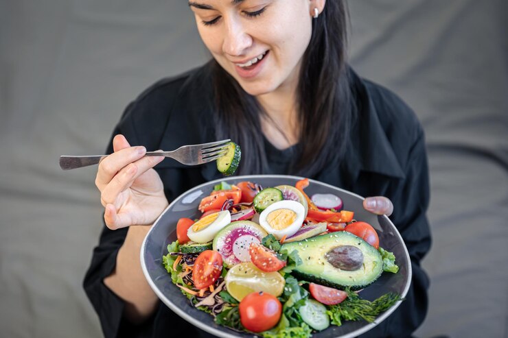 Ensalada apetitosa con verduras frescas y huevos en un plato en manos femeninas