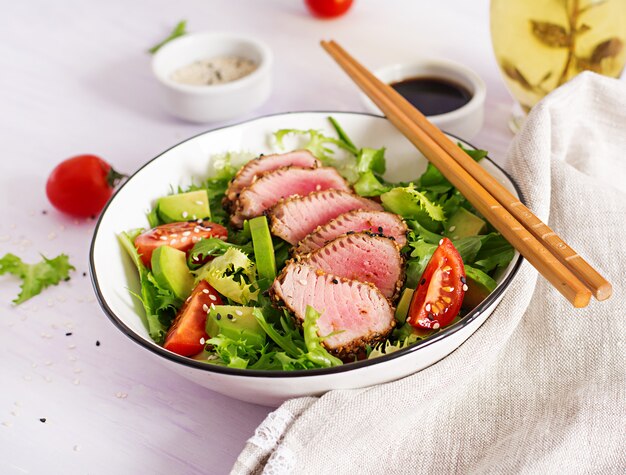 Ensalada de atún. Ensalada tradicional japonesa con trozos de atún ahi a la parrilla medio raro y sésamo con vegetales frescos en un tazón.