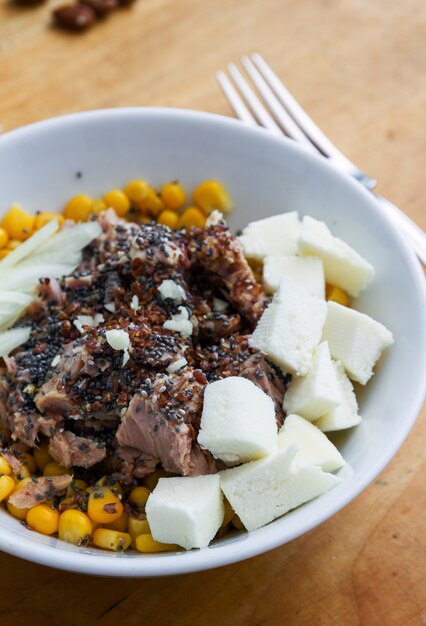 Ensalada de atún sobre una mesa marrón con una cebolla de queso de tenedor plateado