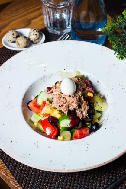 Ensalada de atún con tomate, pepino, maíz y huevo encima