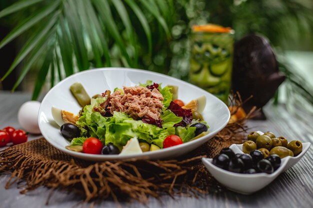 Ensalada de atún con tomates cherry y aceitunas en un plato blanco