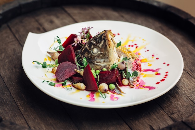 Ensalada con cabeza de pescado en barril de madera