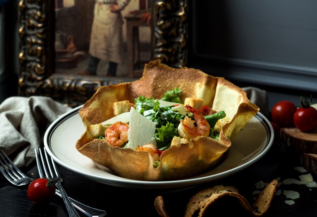 Ensalada de camarones con queso y lechuga en un tazón crujiente de pan plano