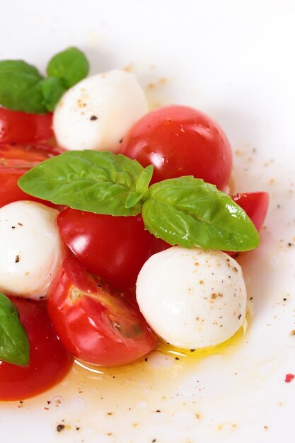 Ensalada caprese con mozzarella, aceite de oliva y hojas de albahaca