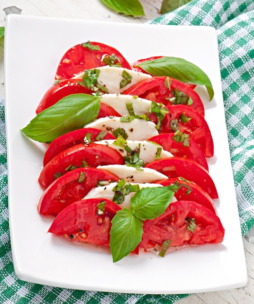 Ensalada caprese. Rodajas de tomate y mozzarella con hojas de albahaca.