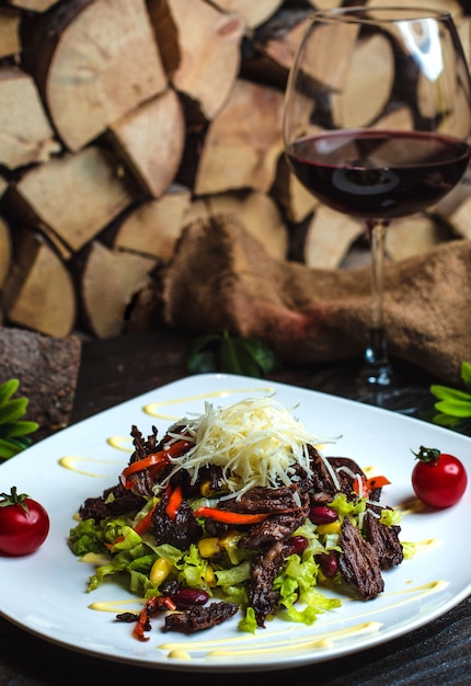 Foto gratuita ensalada de carne con frijoles y una copa de vino tinto