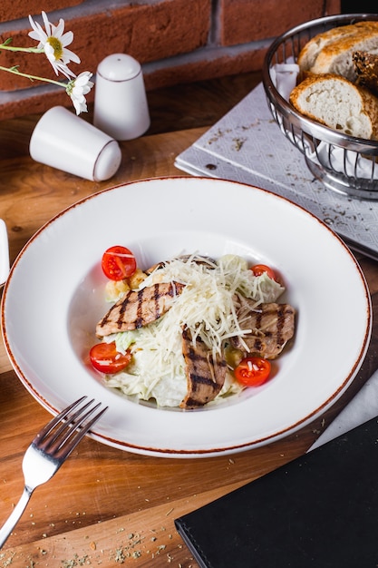 Ensalada de carne con lechuga, tomate y queso rallado.