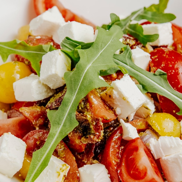 Ensalada de cerca con queso feta, tomates secados al sol y rúcula