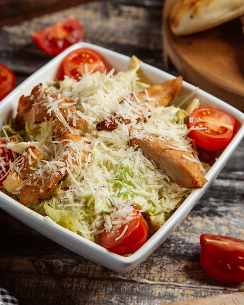 Ensalada césar con filete de pollo a la parrilla, queso y tomates.