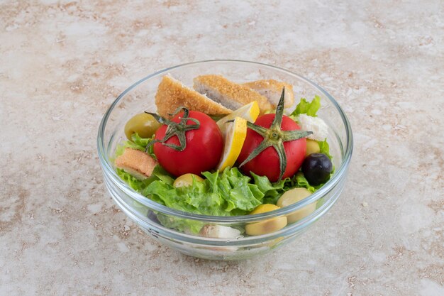 Ensalada César con hierbas, verduras y nuggets de pollo.