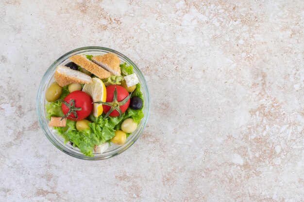 Ensalada César con nuggets de pollo, hierbas y tomates cherry.