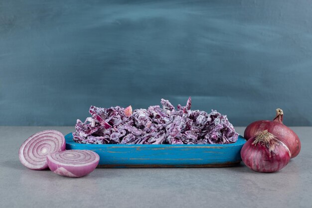 Ensalada de col y cebolla morada picada en un plato sobre la mesa de hormigón.