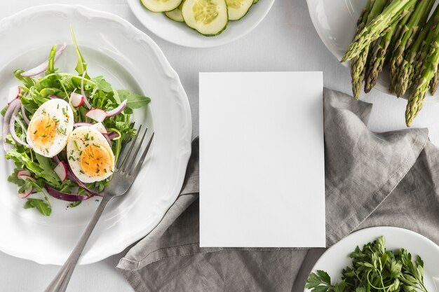 Ensalada deliciosa endecha plana en un plato blanco con tarjeta vacía