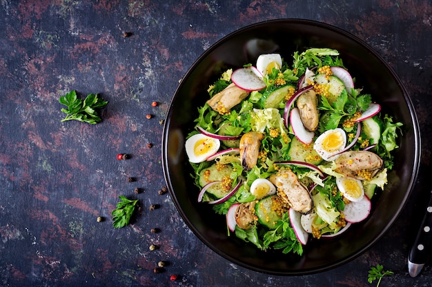 Ensalada dietética con mejillones, huevos de codorniz, pepinos, rábanos y lechugas. Comida sana. Ensalada de mariscos. Vista superior. Endecha plana.