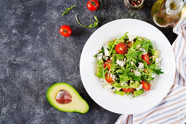 Ensalada dietética con tomate, queso azul, aguacate, rúcula y piñones.