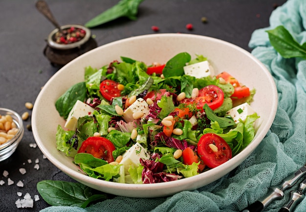 Foto gratuita ensalada dietética con tomate, queso feta, lechuga, espinacas y piñones.