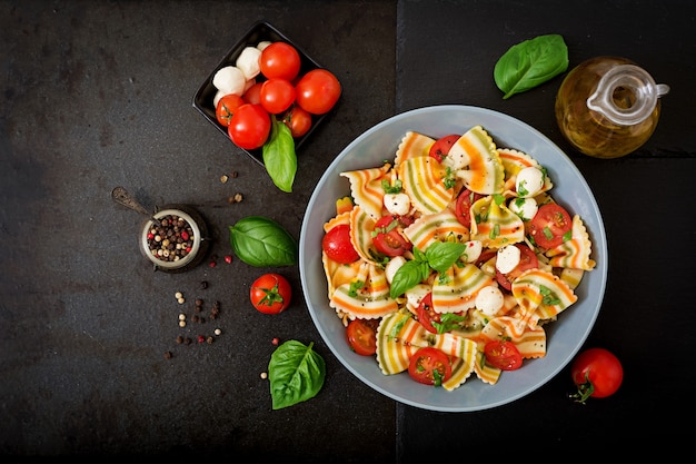 Ensalada farfalle color pasta con tomate, mozzarella y albahaca.