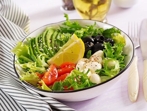 Ensalada fresca con aguacate, tomate, aceitunas y mozzarella en un tazón