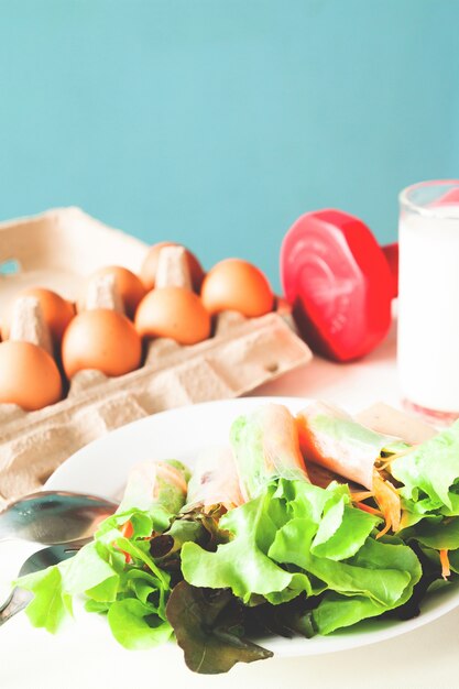 Ensalada fresca con huevo y leche, menú saludable con pesas rojas, concepto de estilo de vida saludable