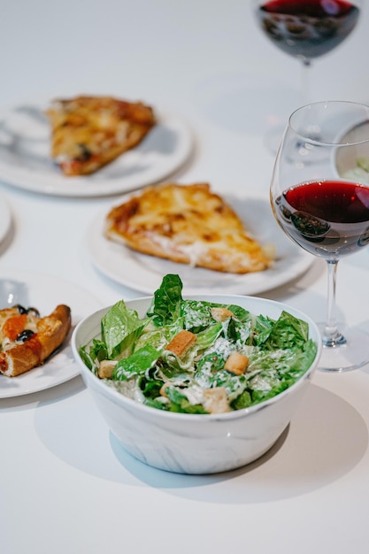 Ensalada fresca con porciones de pizza en los platos y una copa de vino