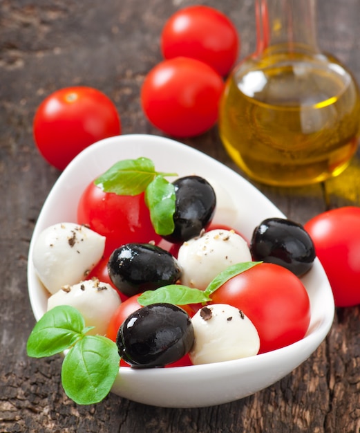 Ensalada fresca con tomates cherry, albahaca, mozzarella y aceitunas negras.