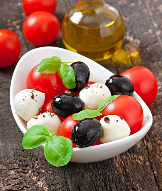 Ensalada fresca con tomates cherry, albahaca, mozzarella y aceitunas negras.