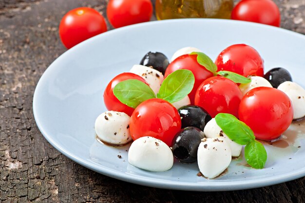 Ensalada fresca con tomates cherry, albahaca, mozzarella y aceitunas negras.