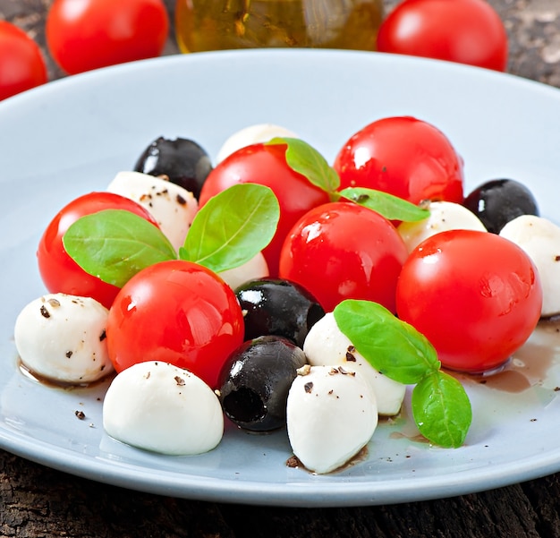 Ensalada fresca con tomates cherry, albahaca, mozzarella y aceitunas negras.